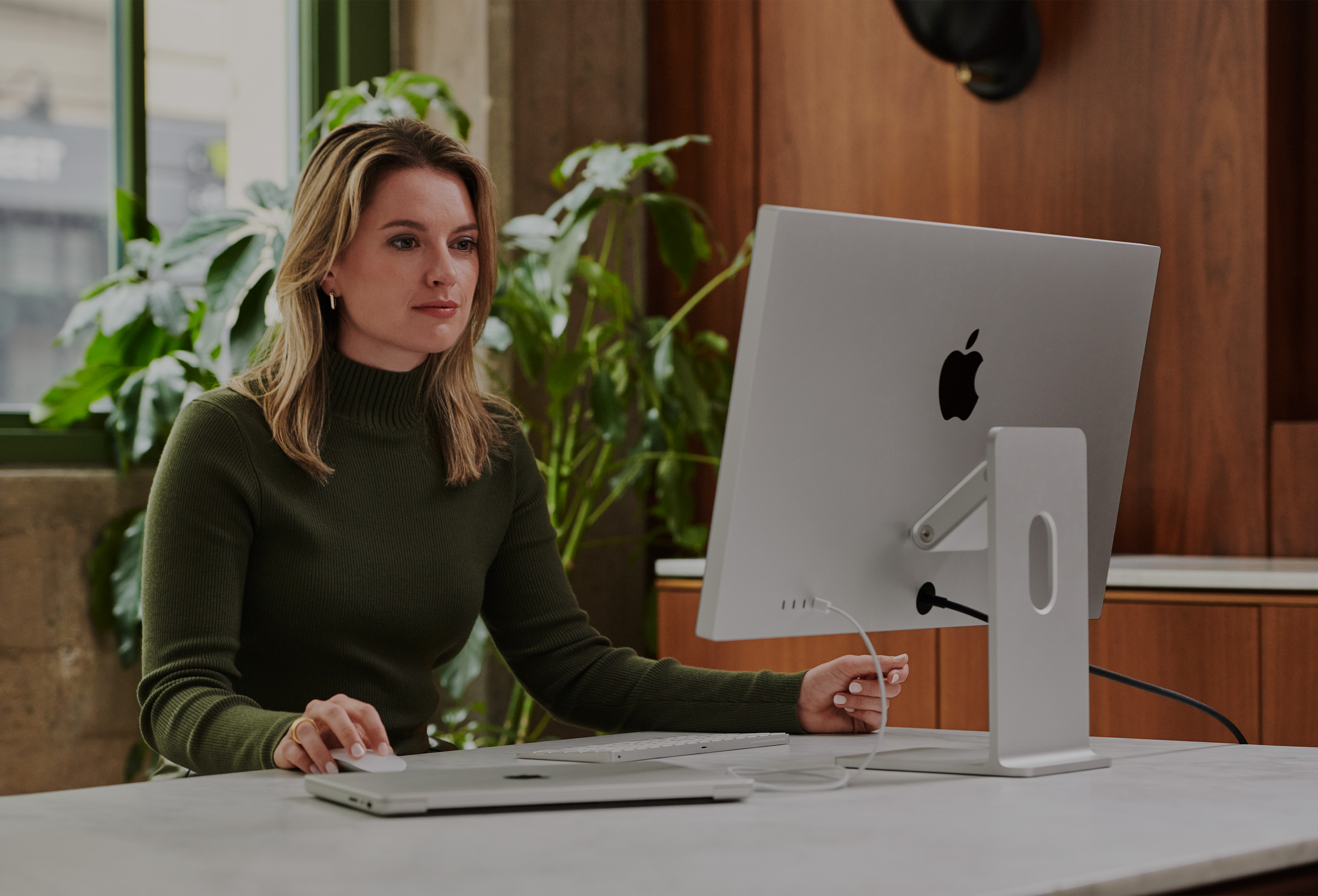 Profissional de marketing trabalhando em frente à tela de um Mac.